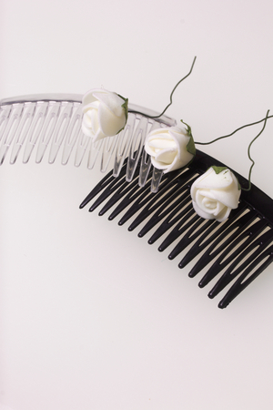 Hair care. Accessories and decorations. Two scallops for hair are transparent and black in color. Artificial rose flowers are beige for interweaving or decorating. On a white background.の写真素材