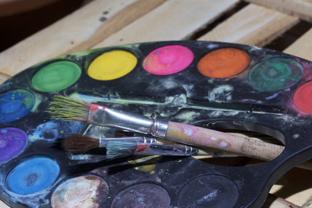 Paints and paint brushes lie on a wooden plank of boards.の写真素材