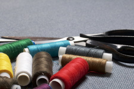 Coils of thread of different colors on a gray fabric background and scissors.の写真素材