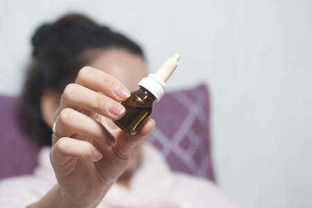 Nasal drops. The woman holds the bottle in front of her in her outstretched hand.の写真素材