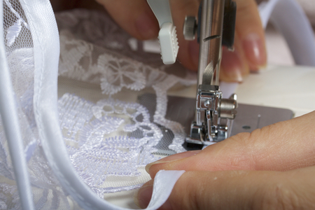 A woman works on a sewing machine. Sewing of lace fabric.の写真素材