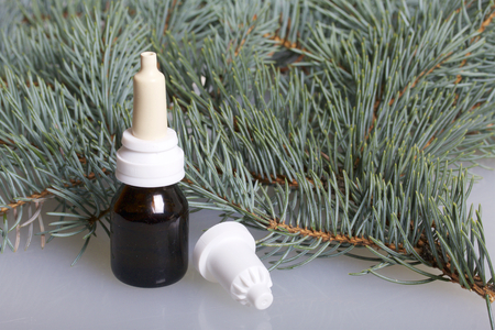 Spray nasal. The bottle with the medicine, with the cap removed, stands on the white surface of the table. Surrounded by branches of blue spruce.の写真素材