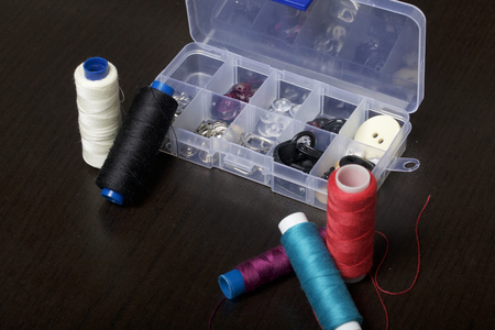 On the surface of the table is a box with sewing accessories. Several coils of thread lie next to each other.の写真素材