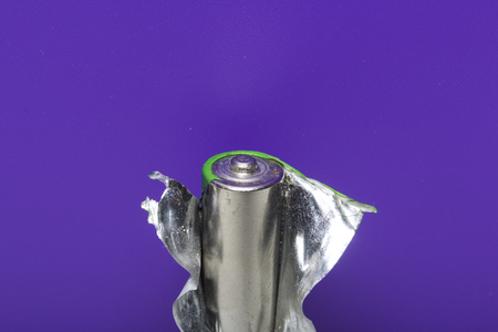 The used battery with the removed covering on a lilac background. Environmental protection, recycling of used batteries.の写真素材