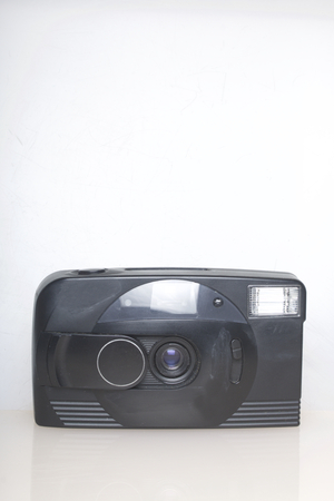 Old semi-automatic camera. Lies on a white surface. View from above.