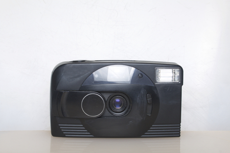 Old semi-automatic camera. Lies on a white surface. View from above.