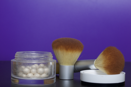Golden highlighter in the form of balls in an open jar. Next to it is a cosmetic brushes for applying it.の写真素材