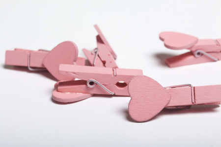 Decorative clothespins with decoration in the form of a heart are scattered on the white surface of...