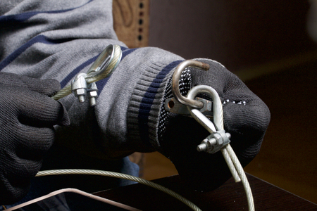 Computer security. Protection of access to data. The tablet is protected by a security cable and a lock. An attacker with gloves tries to open the lock and get access to the computer.の写真素材