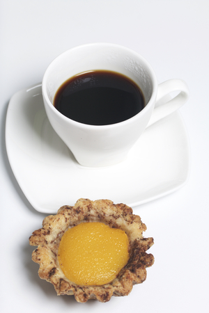 On the white surface of the table is a cup of fragrant coffee on a saucer. There is a cake nearby.の写真素材