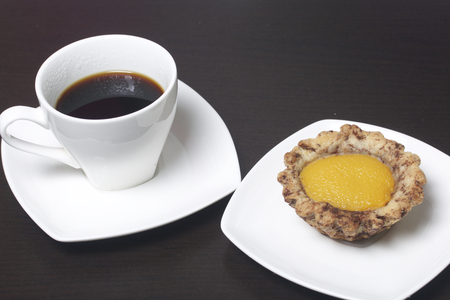 A cup of coffee is on the saucer. There is a cake on the saucer.の写真素材