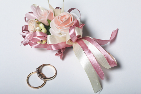Wedding decor. Boutonniere groom with the bride, their wedding rings, lie on a white surface.の写真素材