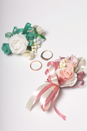 Wedding decor. Boutonniere groom with the bride, their wedding rings, lie on a white surface.の写真素材