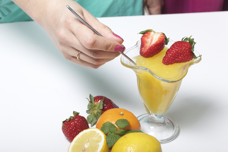Jelly in the crockery, decorated with strawberries and mint. Next to the table are fruits: mandarins, lemon and bayut.の写真素材