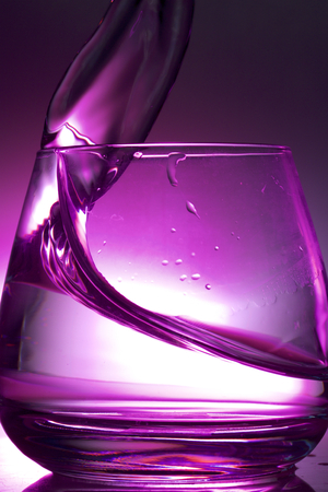 Splash the liquid in a glass. Photographed on a colored background. Backlight control.の写真素材