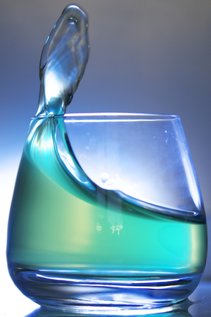 Splash the liquid in a glass. Photographed on a colored background. Backlight control.の写真素材