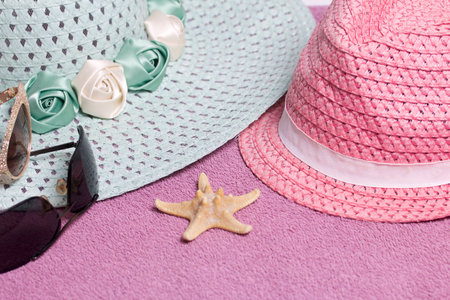 Going on vacation on the beach. Hat for protection from the sun and a pair of sunglasses. Against the background of a beach towel.の写真素材