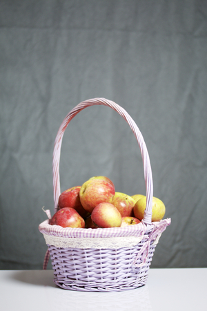 Autumn harvest of apples. Apples in a wicker from a vine basket. On a gray background.の写真素材