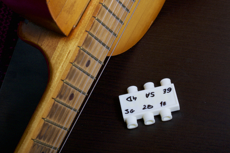 Acoustic guitar and tuning fork to adjust it. On a dark background.