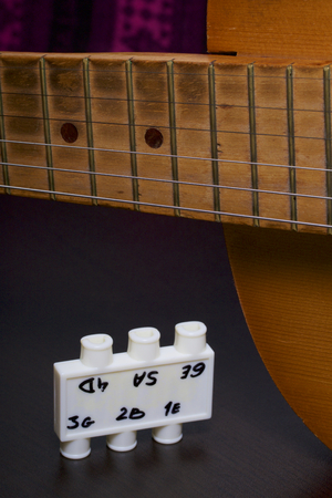 Acoustic guitar and tuning fork to adjust it. On a dark background.