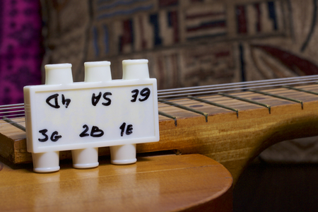 Acoustic guitar and tuning fork to adjust it. On a dark background.の写真素材