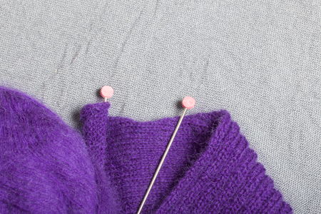 Knitting with steel knitting needles. A ball of purple thread and steel knitting needles in an...