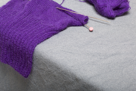 Knitting with steel knitting needles. A ball of purple thread and steel knitting needles in an...