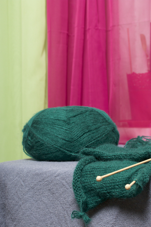 Knitting with wooden knitting. A ball of dark green thread and wooden knitting needles in an unfinished knit.の写真素材