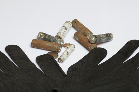 Used finger-wound batteries covered with corrosion. Next working gloves. Recycling.