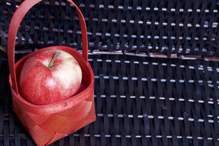 Ripe aromatic apples in a red wicker basket. Against the background of a wicker basket of wicker.の写真素材
