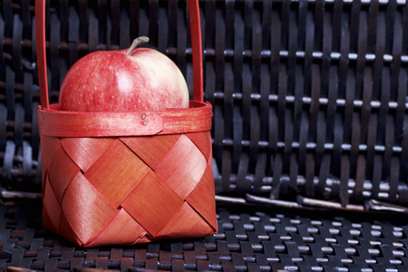 Ripe aromatic apples in a red wicker basket. Against the background of a wicker basket of wicker.の写真素材