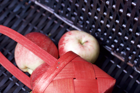 Ripe aromatic apples in a red wicker basket. Against the background of a wicker basket of wicker.の写真素材