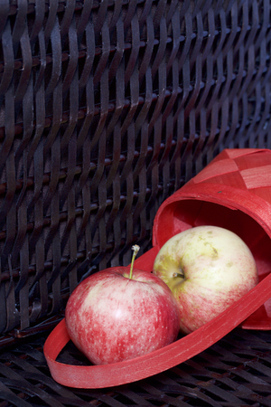 Ripe aromatic apples in a red wicker basket. Against the background of a wicker basket of wicker.の写真素材