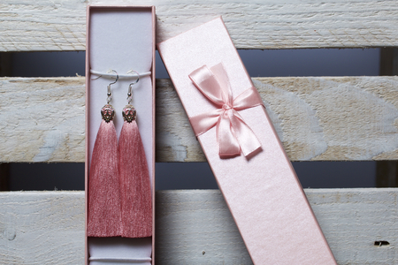 Earrings made of viscose handmade. Together with wrapping gift boxes. Against the background of a wooden box.の写真素材