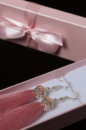 Earrings made of viscose handmade. Together with wrapping gift boxes. Against the black background.の写真素材