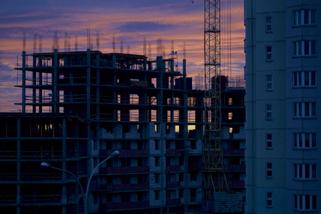 Tower cranes on the construction of a building with a frame of reinforced concrete. On the background of the dawn.の写真素材