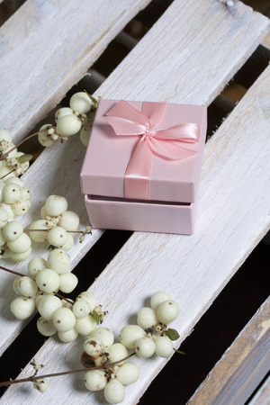 Wrapping presents. Gift boxes. Nearby there is a branch from a bush with autumn fruits of white color. Against the background of a wooden box.の写真素材