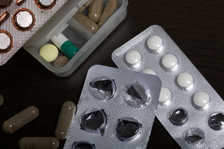 Tablets in the table and blister. Some started. Nearby are a few pills. On a dark background.の写真素材