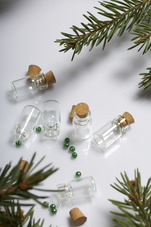 Glass bottles with corks. For beads. Located among the branches of spruce on a white background.の写真素材