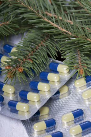 The blisters with pills. Different colors. Spruce  branches. On a wooden box.の写真素材