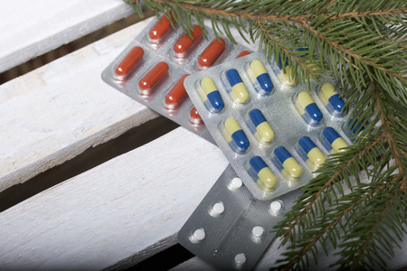 The blisters with pills. Different colors. Spruce and pine branches with cones. On a wooden box.の写真素材