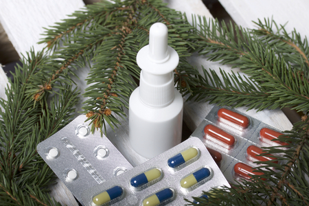 The blisters with pills. Different colors. Nasal spray. Spruce branches. On a wooden box.の写真素材