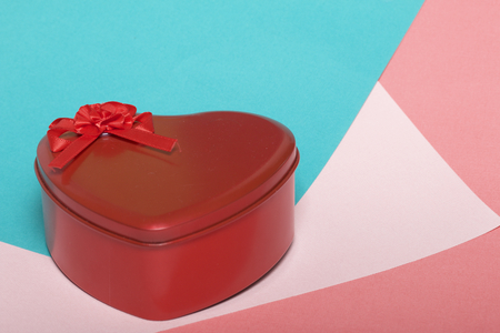 A box in the form of a red heart with a gift. On a background of multicolored paper.の写真素材
