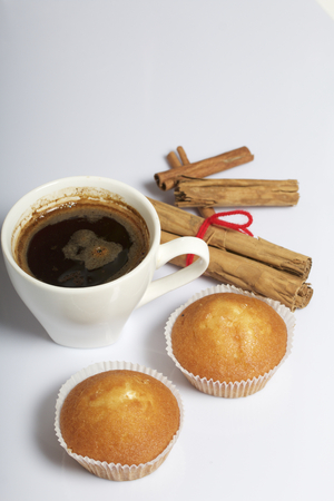A cup of freshly brewed coffee and muffins. Nearby are cinnamon sticks. On a white background.の写真素材