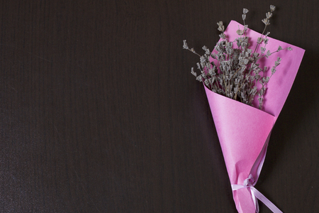 A bouquet of dried flowers, wrapped in colored paper. On a dark background.の写真素材