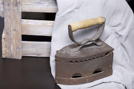 Old iron, heated by hot coals. Standing next to a wooden box and linen cloth.の写真素材