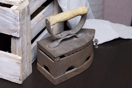 Old iron, heated by hot coals. Standing next to a wooden box and linen cloth.の写真素材