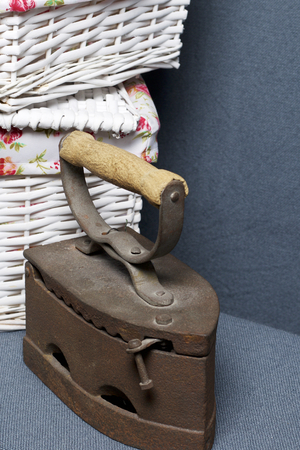 Old iron, heated by hot coals. Located on gray fabric. Nearby are wicker baskets.の写真素材