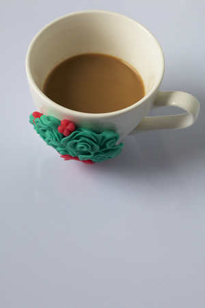 Coffee mug decorated with polymer clay flowers. Crafts from polymer clay. Mug decorated with stucco made of polymer clayの写真素材