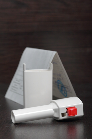 Inhaler for the treatment of respiratory organs. Spray can and cap white. Next recipe to buy. On a dark surface.の写真素材